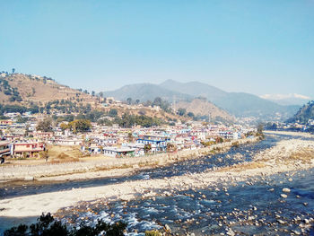 Aerial view of townscape by mountain against sky