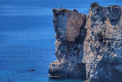 People on rock by sea