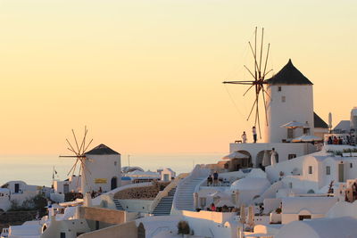 Traditional windmills in village at santorini against clear sky during sunset