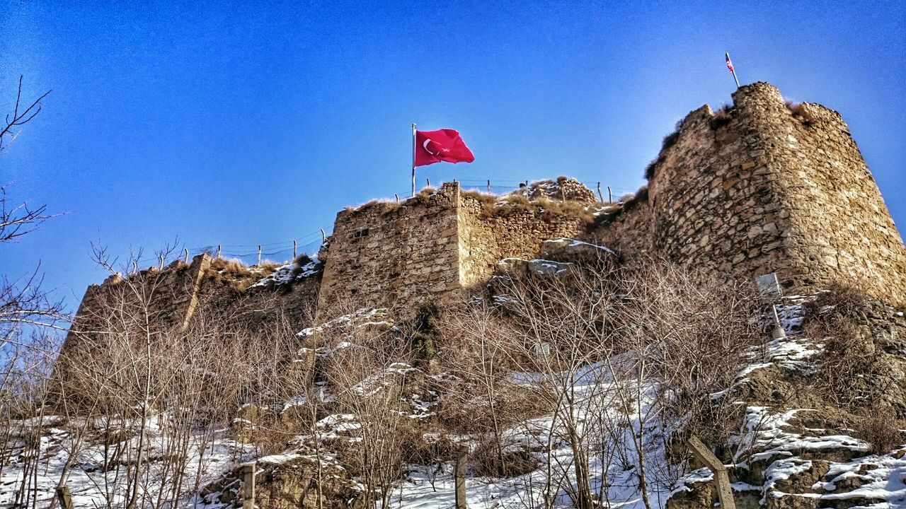 clear sky, blue, architecture, built structure, building exterior, low angle view, flag, guidance, copy space, day, sky, nature, outdoors, sunlight, identity, no people, direction, lighthouse, national flag, incidental people