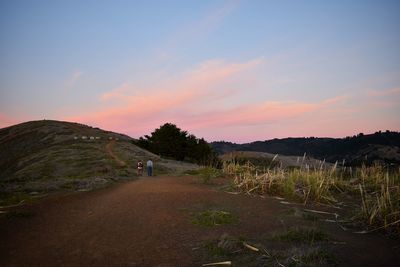 Man walking on mountain against sky during sunset