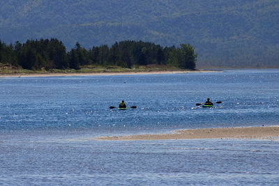 People on boat in sea against sky