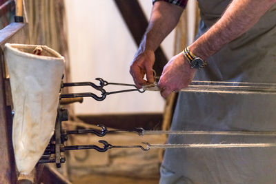 Midsection of man tying ropes on hook