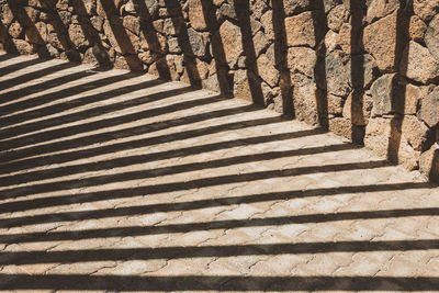 High angle view of shadow on walkway and stone wall