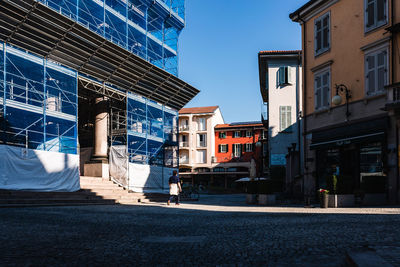 Street by buildings against blue sky