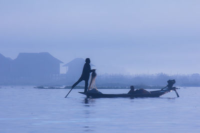 Fisherman fishing on lake against sky