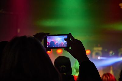 Silhouette person photographing music concert