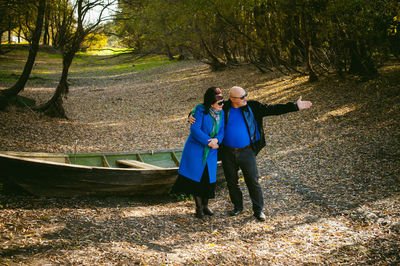 Full length of couple standing by tree in forest