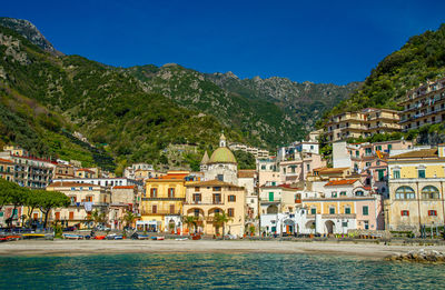 Buildings by sea against sky