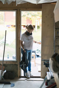 Full length of woman with tool belt entering in house being renovated