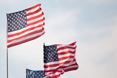 Low angle view of american flags against sky