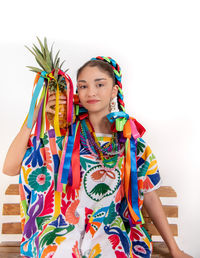 Portrait of young woman holding umbrella against white background