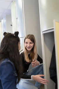 Teenage girls talking near lockers