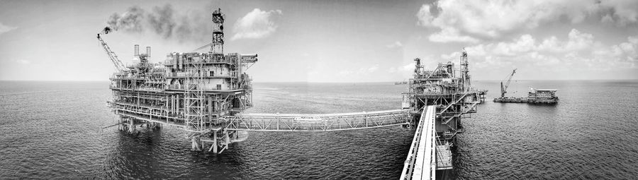 Cranes in sea against sky