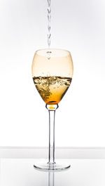 Close-up of wineglass on glass against white background