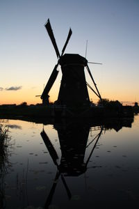 Traditional windmill with reflection against sky during sunset