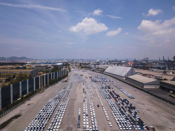 Aerial logistics commercial vehicles waiting to be load on to a car carrier ship at dockyard