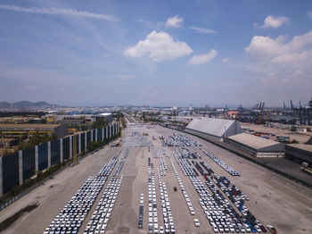 Aerial logistics commercial vehicles waiting to be load on to a car carrier ship at dockyard