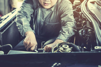 Midsection of mechanic repairing car at garage