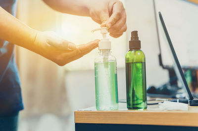 Close-up of hand holding bottle on table