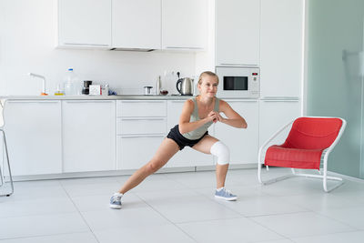 Fitness, home and diet concept. smiling young woman stretching at home, in the kitchen