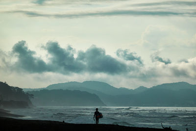 Man standing at beach against sky