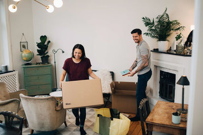 Happy couple unpacking boxes in living room at new home