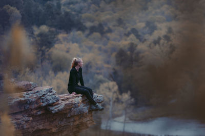 Side view of woman sitting on rock