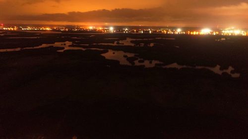 Illuminated beach against sky at night