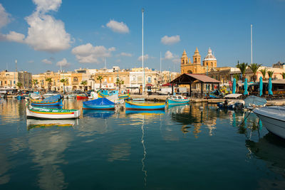 Traditional colorful luzzu fishing boats arriving and anchoring in marsaxlokk village harbor