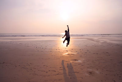 Man on beach against sky during sunset