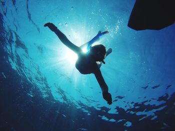 Low angle view of woman swimming undersea during sunny day