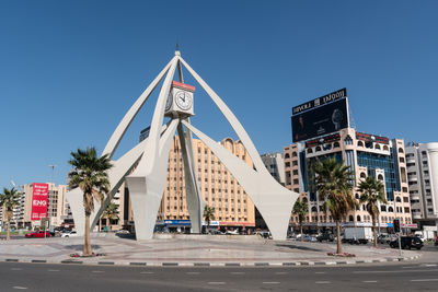 Low angle view of road by building against clear blue sky