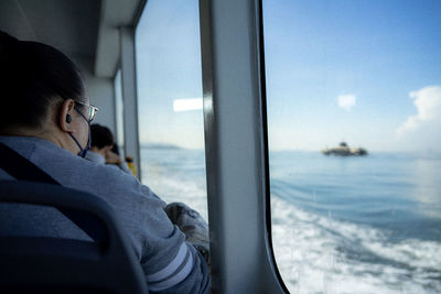 Side view of woman looking through window