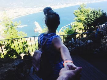 Rear view of woman sitting on railing against sky