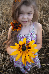 Portrait of cute girl with yellow flowers on field