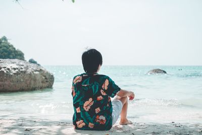 Rear view of boy sitting on beach