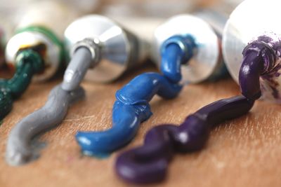 Close-up of colorful paints spilled from tubes on wooden table