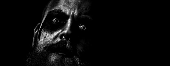 Close-up portrait of spooky man against black background