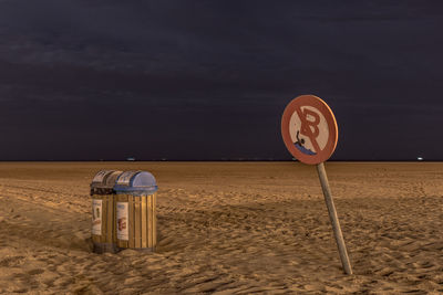 Information sign on beach against sky at night