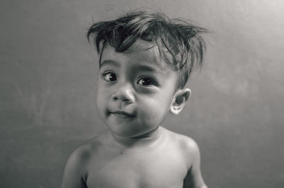 Portrait of cute shirtless boy against wall