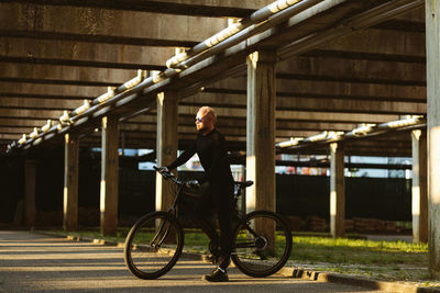 Side view of man standing on bicycle