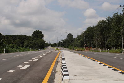 Road by trees against sky