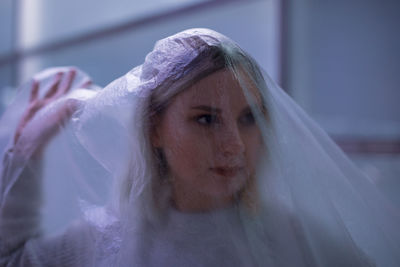 Young woman covered with plastic looking away