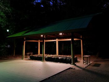 Illuminated building by trees at night