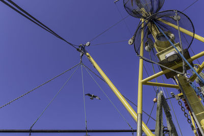 Low angle view of pulley against clear blue sky