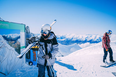 People standing on snow covered mountain against sky