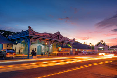 Light trails on road in city against sky at sunset