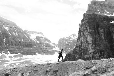 Rear view of man on rocky mountain against sky