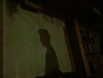 Low angle view of silhouette man standing against wall at night